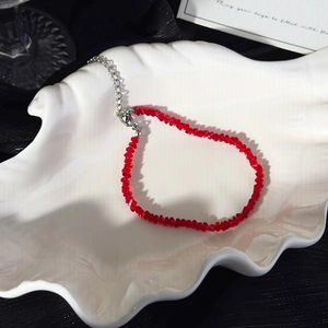 Detail of red faceted crystal bead bracelet with silver lobster clasp on a shell tray