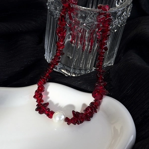 Détail de perles en pierre bordeaux et une perle blanche sur un collier élégant