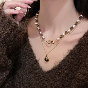 Détail d'un collier à deux rangs avec perles, œil de tigre et pendentif doré raffiné