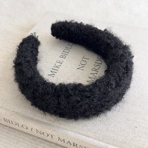 Close-up of black fuzzy lamb wool headband texture on an artistic book background