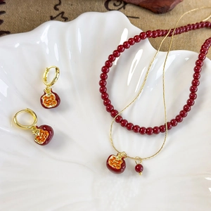 Macro shot of red pomegranate jewelry set with gold details on a textured plate