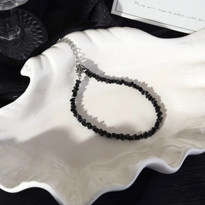 Close-up of black beaded stone bracelet with silver adjustable chain in shell dish