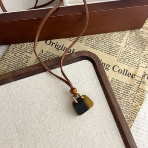 Dettaglio macro del ciondolo borsa in pietra occhio di tigre su collana in velluto