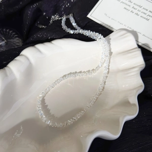 Detail of irregular white crystal beaded necklace on shell plate with black velvet background