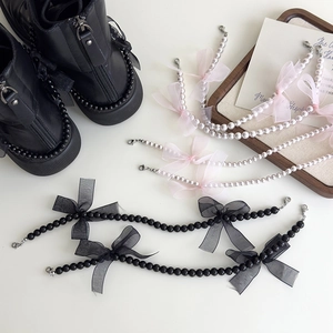 Vue détaillée du nœud en dentelle et de la chaîne de perles sur des bottes en cuir noir