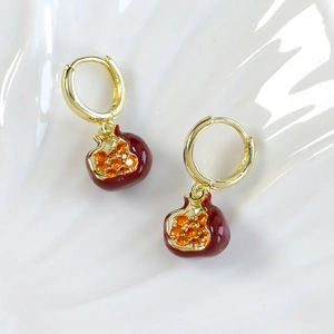 Detail of gold pomegranate earrings with red enamel and amber crystal seeds decoration