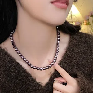 Dettaglio della collana di perle di vetro viola scuro con lucentezza metallica sul collo