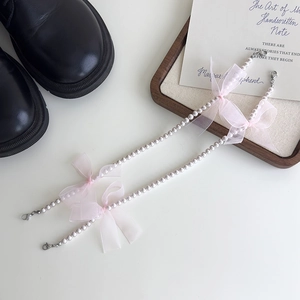 Vue détaillée des chaînes de chaussures en perles avec nœuds en organza rose et fermoirs