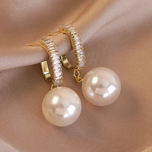 Eleganti orecchini pendenti in oro con zirconi baguette e grandi perle champagne