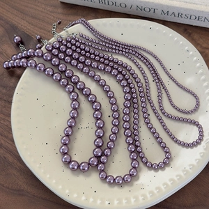 Dettaglio della collana di perle viola prugna con diverse dimensioni di perle e chiusura