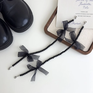 Détail de breloques de chaussures avec perles noires et nœuds en dentelle élégants
