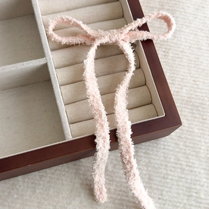 Dettaglio del fermaglio per capelli a fiocco rosa in peluche con nastri lunghi
