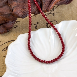 Macro shot of polished red garnet necklace beads resting on a white shell porcelain dish