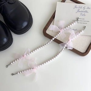 Détail de chaînes de chaussures en perles avec nœuds en dentelle rose et fermoirs métalliques