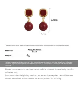 Vue détaillée de boucles d'oreilles perles rouges avec base dorée mesurant 2,4cm sur 1cm