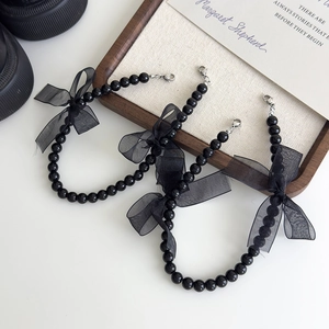 Détail de trois chaînes de chaussures à perles noires avec nœuds en organza et fermoirs