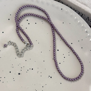 Dettaglio di collana con perle di vetro viola scuro con chiusura a moschettone in argento