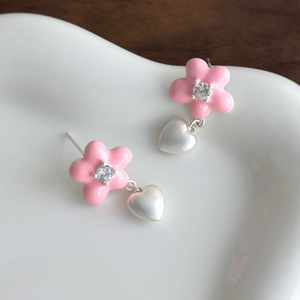 Vue détaillée des boucles d'oreilles fleurs roses avec cœurs blancs sur plat en céramique