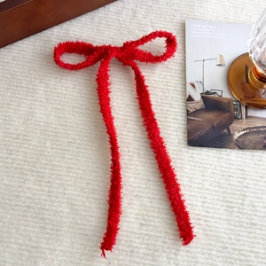Dettaglio del fermaglio per capelli a fiocco rosso felpato con morbida trama bouclé