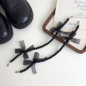 Détails de chaînes de chaussures en perles noires avec nœuds en dentelle et fermoirs