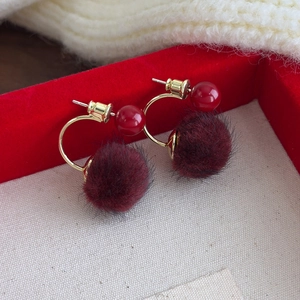 Detail view of winter red faux fur pom-pom earrings with golden metal and red beads