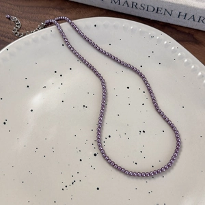 Dettaglio della collana di perle di vetro viola scuro con catenella di estensione in argento