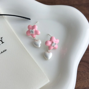Détail de boucles d'oreilles fleur rose en émail avec cœurs et zircons étincelants