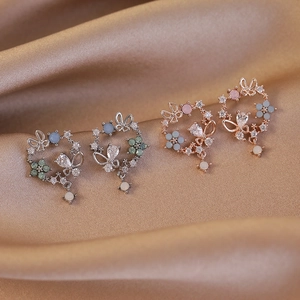 Elegant floral and butterfly stud earrings with zircon stones on silk background