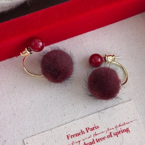 Detail of vintage French style earrings featuring burgundy plush balls and gold metal hoops