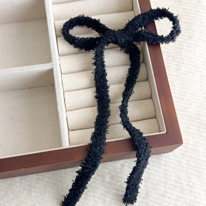 Dettaglio del fiocco per capelli in peluche nero con lunghi nastri su espositore in velluto