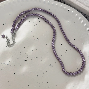 Dettaglio della collana di perle di vetro viola scuro con chiusura in argento su vassoio