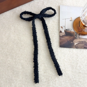 Dettaglio del fermaglio per capelli a fiocco in peluche nero con lunghi nastri su tappeto