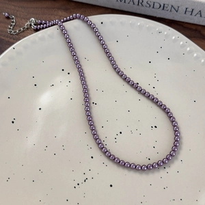 Dettaglio della collana di perle viola scuro con chiusura a moschettone argento e catena