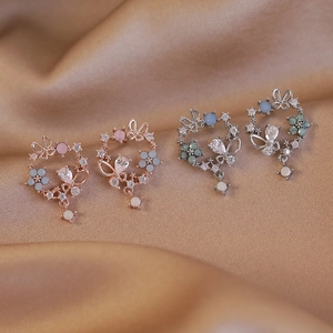 Macro shot of butterfly and flower earrings with zircon in rose gold and silver finish