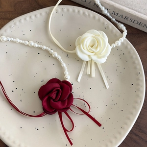Eleganti collane di perle con fiori di camelia rossi e bianchi su vassoio di ceramica