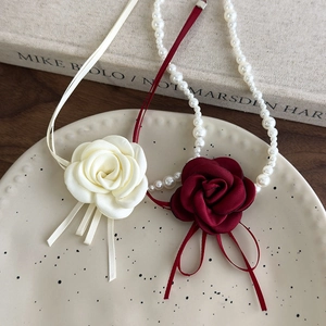 Dettaglio della collana a fiore di camelia rossa con petali di seta e perle eleganti