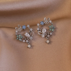 Detail of silver butterfly flower earrings with gemstones on champagne silk