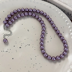 Dettaglio di collana con perle viola scuro e chiusura in argento su vassoio