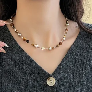 Détail de collier vintage en œil de tigre et perles avec accents métalliques sur le cou