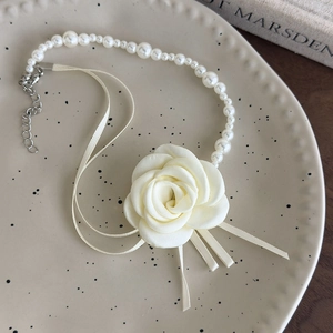 Primo piano di un choker di perle con camelia in tessuto bianco e nastri di seta eleganti