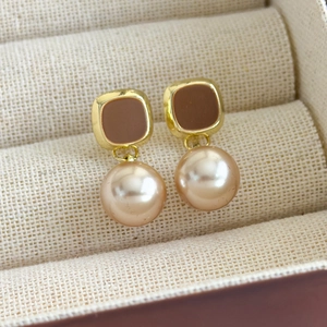 Gros plan sur des boucles d'oreilles perles vintage avec base dorée et émail marron