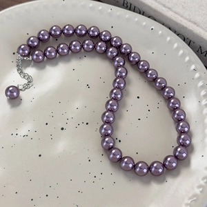 Macro di una collana di perle di vetro viola scuro con chiusura a moschettone in argento