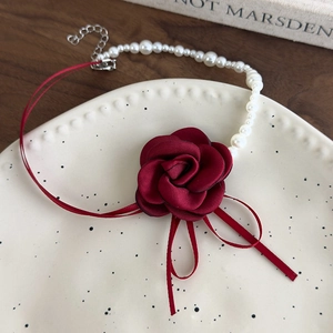 Dettaglio della collana a fiore di camelia rossa con perle finte bianche e nastro di seta rossa