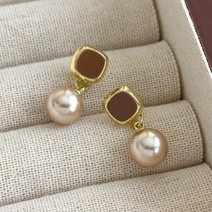Vue macro détaillée de boucles d'oreilles émaillées vintage avec perles champagne