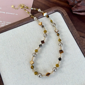 Vue détaillée du collier avec pierres d'oeil de tigre, perles et fermoir mousqueton doré