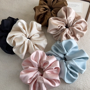 Detail showing set of 6 oversized satin scrunchies with silky glossy texture in multiple colors
