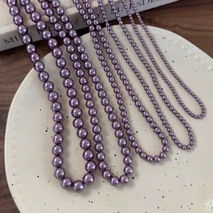 Elegante set di collane di perle di vetro viola in varie dimensioni su piatto di ceramica