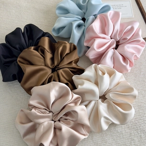 Macro detail of large satin hair scrunchies in six elegant colors with silky texture