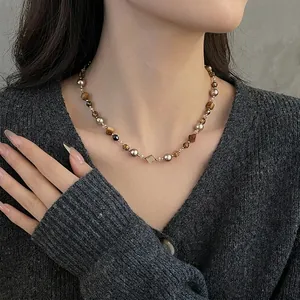 Collier en perles d'oeil de tigre et perles dorées sur un cardigan gris foncé
