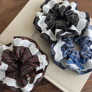 Detailed view of plaid scrunchies with white lace edges and delicate ribbon bows